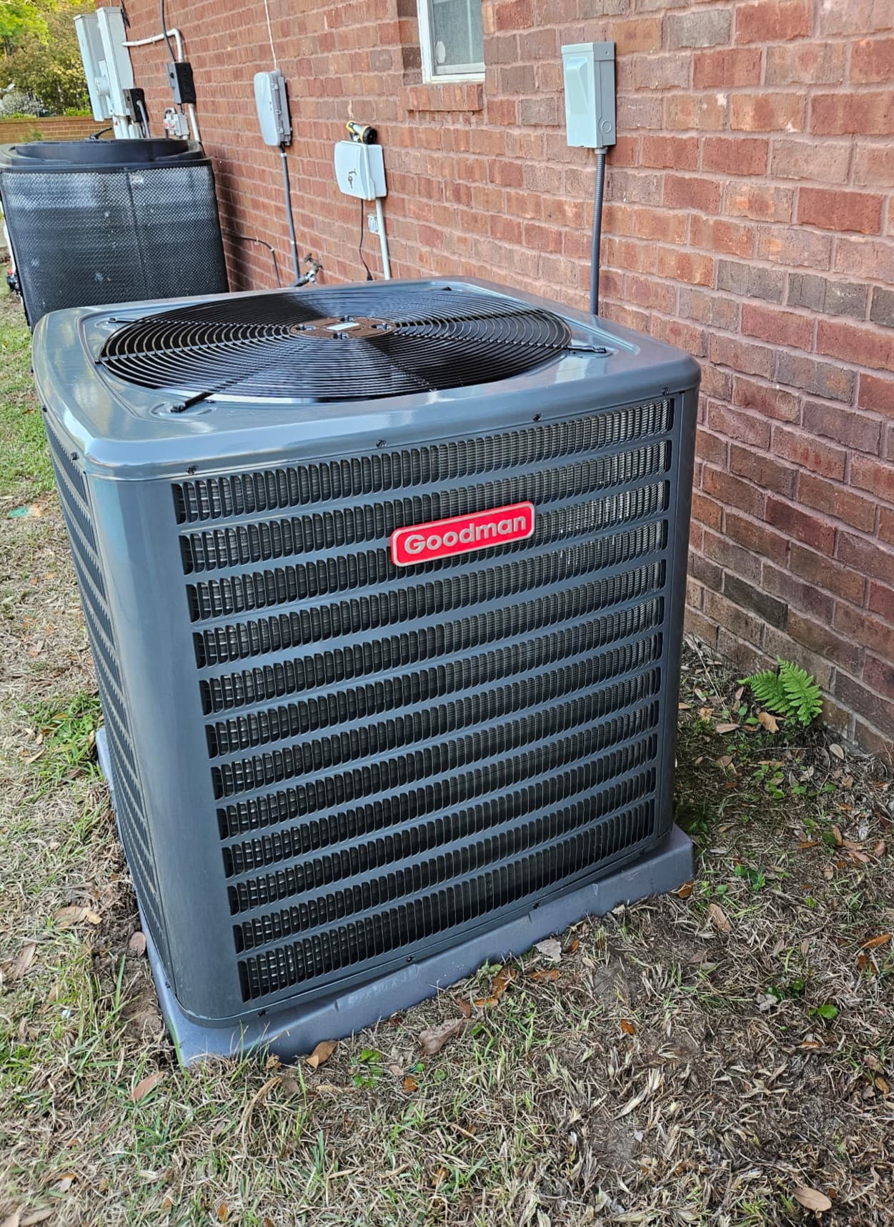 New residential air conditioning condenser installed beside a brick home